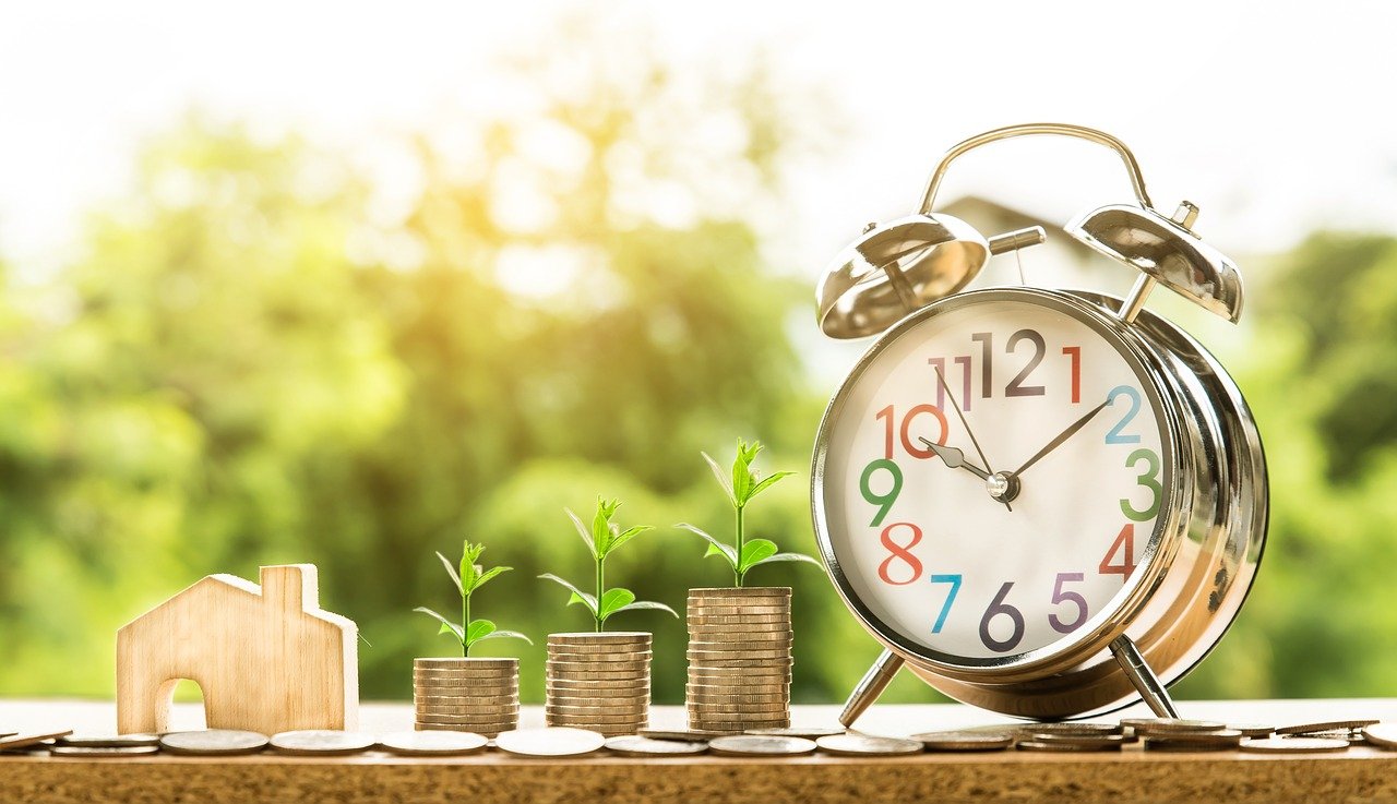 representation of export pricing strategy with piles of coins, a clock and a wooden house on a table